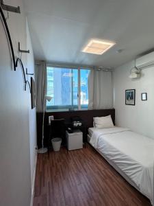 釜山Ekonomy Haeundae Hostel的一间卧室配有一张床、一张书桌和一个窗户。
