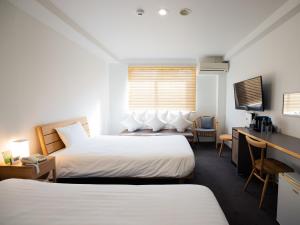 鹿儿岛You Style Hotel MARINE的酒店客房配有两张床和一张书桌