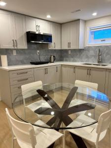 多伦多BRAND NEW home with EXCLUSIVE Bathroom的厨房配有玻璃桌和白色橱柜