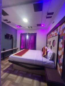 乌提Ooty OWLS NEST INN的一间卧室配有一张紫色照明的大床