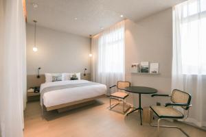 北京念念行旅酒店(北京南锣鼓巷北新桥地铁站店)的卧室配有一张床和一张桌子及椅子