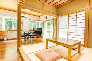 SengokuharaGreen Oasis Cottage Hakone Sengokuhara - グリーンオアシスコテージ箱根仙石原的一间带桌子的客厅和一间餐厅