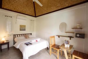 科隆Sunz en Coron Resort的一间卧室配有一张床、一张桌子和一张桌子