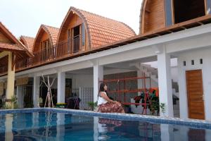 珀尼达岛Garuda Hostel & Accomodation Nusa Penida的站在带游泳池的房子前面的女人