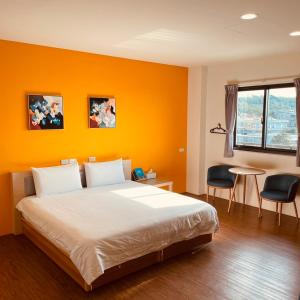 小琉球岛好客文旅的一间卧室设有橙色墙壁、一张床和一张桌子