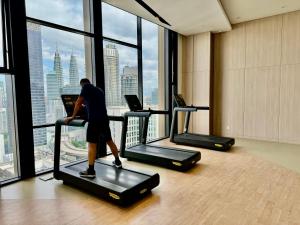 吉隆坡Axon Residence By Luxury Suites的站在健身房跑步机上的人,看着窗外