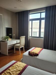 Vị ThanhKhách sạn Hậu Giang的一间卧室设有两张床、一张桌子和一个窗口。