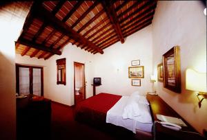 曼恰诺皮亚内提农场酒店的一间卧室配有一张带红色毯子的大床