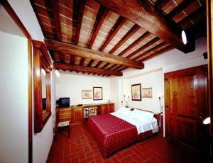 曼恰诺皮亚内提农场酒店的一间卧室配有一张床、一张书桌和一台电视