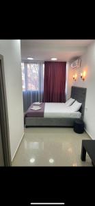 斯科普里Hotel Fama的一间卧室配有一张带红色窗帘的大床