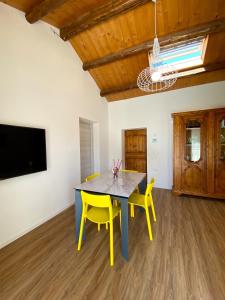 法诺Levante Flat - 100 m from the beach的一间带桌子和两张黄色椅子的用餐室