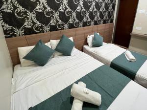 关丹KUANTAN BESERAH BUDGET HOTEL的一间卧室配有两张带绿色和白色枕头的床