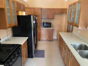 RichmondOasis @ Richmond Estate - Ocho Rios - St Ann的厨房配有木制橱柜和黑色冰箱。