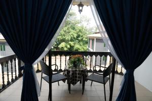 马六甲Putera Island Resort的阳台配有一张桌子和椅子,阳台配有蓝色窗帘