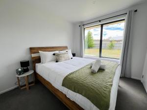 箭镇Leisure Holiday Home Lake Hayes Easte Queenstown的一间卧室设有一张大床和一个大窗户