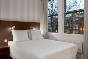 阿姆斯特丹阿姆斯特丹市中心NH酒店的窗户客房内的一张白色床