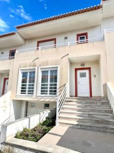 阿托吉亚达巴莱亚Fantastic 3 bedroom Villa - Peniche - Mer&Surf的白色的房子,有红色的门和楼梯