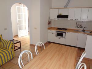 普罗基奥Residence Le Mimose的厨房配有白色橱柜和桌椅