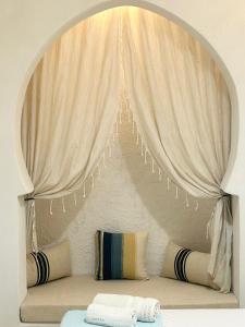 米多恩Hôtel Djerba Authentique - Au centre de Midoun的客房配有带窗帘和枕头的床。