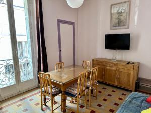 芒通APPARTEMENT MAISON, CENTRE VILLE, PROCHE PLAGE TOUT COMMERCE的一间带桌椅和电视的用餐室