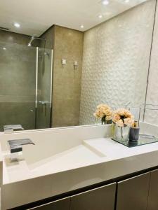 圣保罗Itaim Bibi - The Capital Flat - Apto 1211的浴室配有带镜子和鲜花的盥洗盆