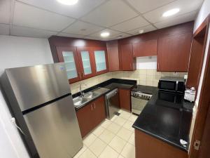 迪拜Sea View Beach Hostel - Walk to Beach - Metro Station - Pool的厨房配有木制橱柜和不锈钢冰箱。