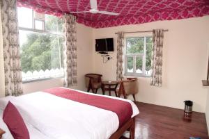 萨瓦伊马多普尔Ranthambhore Tiger Niwas的一间卧室设有床、两个窗户和一台电视。