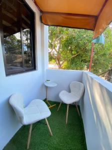 NaicCabuhat-Duco Lodge 3的阳台配有两把椅子和一张桌子,阳台设有窗户