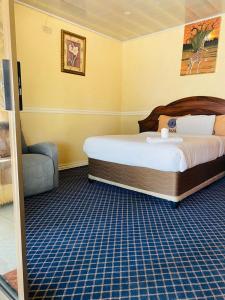 卢萨卡Royal Olympia Lodge Lusaka的一间卧室,卧室内配有一张床和一把椅子