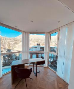 朗斯Exclusive Comfy Apartment in Central Crans-Montana的客房设有桌椅和大窗户。