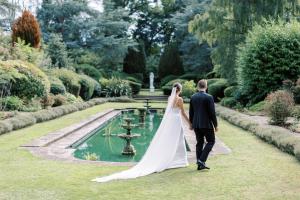 阿斯科特Royal Berkshire的一位新娘和新郎在花园中散步