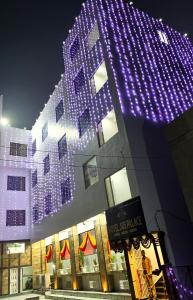 戈勒克布尔HOTEL JVS PALACE的建筑的侧面有紫色的灯