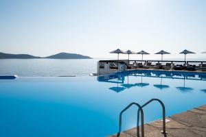 伊罗达Aquila Elounda Village Resort, Suites & Spa的一个带蓝色水和遮阳伞的游泳池