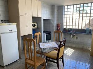 乌贝拉巴Solar dos Costais: casa com 4 suítes climatizadas的厨房配有桌椅和冰箱。