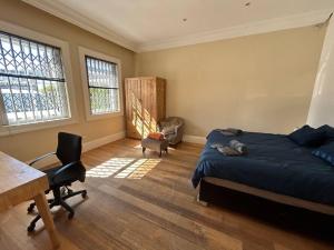 开普敦The Yellow House的一间卧室配有一张床、一张书桌和两个窗户。