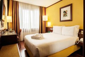 里斯本里斯本大陆假日酒店度假村的酒店客房设有一张白色大床和一张书桌