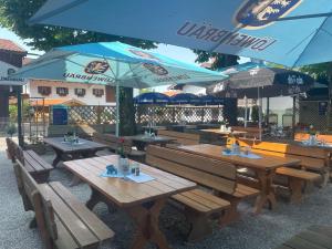 贝内迪克特博依恩Gasthof Herzogstand bei Stefan的餐厅设有木桌和蓝色遮阳伞
