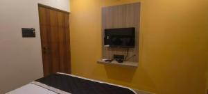 维沙卡帕特南Nebo Suites的一间黄色墙壁上配有电视的房间