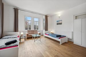 梅青根home2stay worker Apartments Metzingen的一间卧室配有两张床、一张沙发和一把椅子