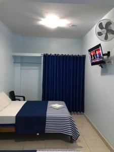 曼克拉Áncora Beach Hotel的一间卧室配有一张蓝色窗帘的床和一台电视