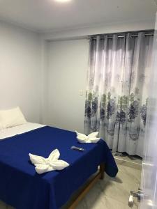 曼克拉Áncora Beach Hotel的一间卧室配有蓝色的床,上面有两朵白色的花