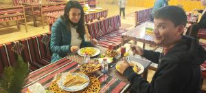 瓦迪拉姆Wadi Rum Aviva camp的坐在餐桌旁吃食物的男人和女人