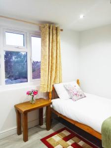 GoodmayesGoodmayes Park Home的一间卧室配有一张床、一张桌子和一个窗户。