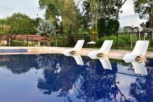 蒙特内哥罗Finca Hotel Los Girasoles的一组坐在游泳池旁的白色椅子