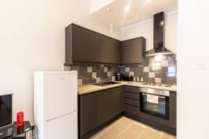 格拉斯哥Stunning Ground Floor flat in Southside.的厨房配有黑色橱柜和白色冰箱。