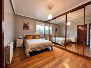 桑坦德Villa Senda costera. Un lugar natural en la ciudad的一间卧室设有两张床和大镜子