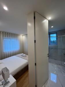 维拉诺瓦-德法马利Brittos Home Lovely Stay - Villa Prime in VN de Famalicão Braga的一间卧室设有一张床和一个玻璃淋浴间