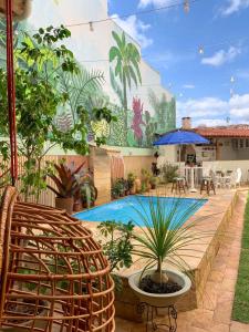 迪亚曼蒂纳POUSADA CAPIM LIMÃO的庭院设有植物和壁画游泳池