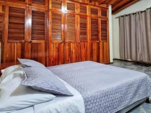 里奥内格罗HOSTAL - Casa Rionegro -10 min del aeropuerto的一间卧室设有木墙和一张带枕头的床。