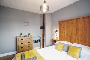 利兹Stylish and cosy cottage in the heart of Yorkshire的一间卧室配有一张带黄色枕头的床和木制床头板
